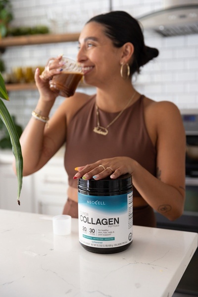 A natural, kitchen-setting image featuring a person drinking the product with the tub clearly visible in the foreground.